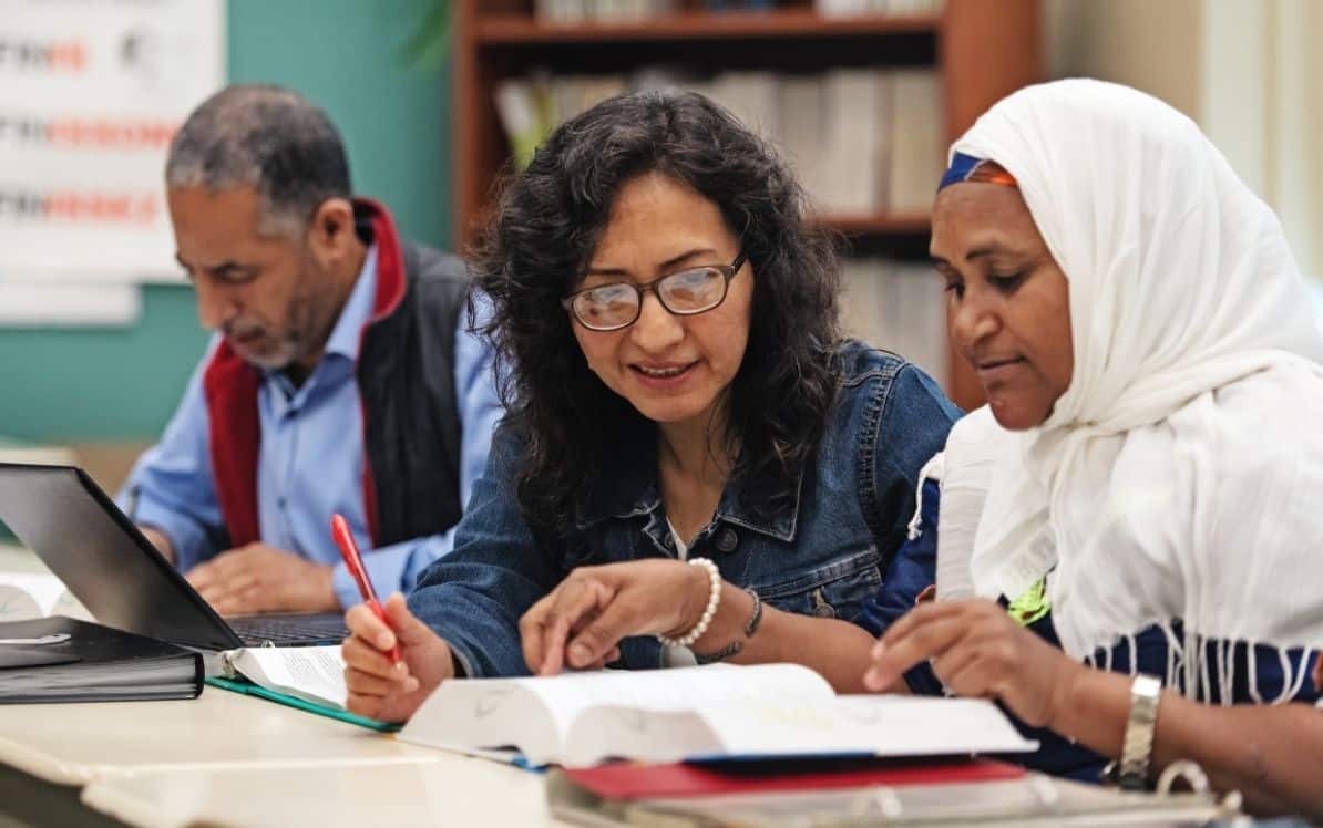 Three people focusing on study materials at a table.