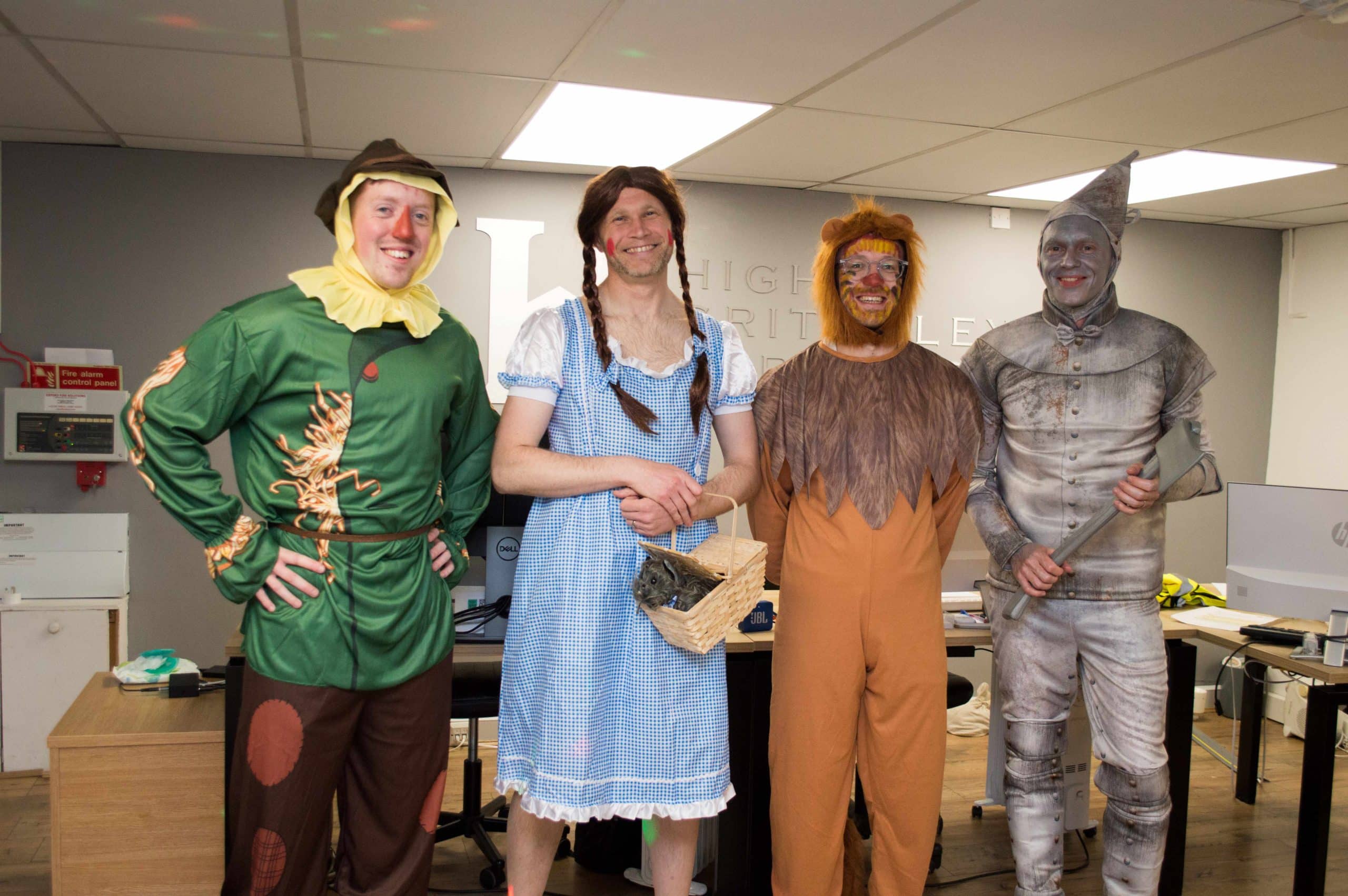 Higham Critchley Barrows Oz Four people dressed as Wizard of Oz characters standing in an office.