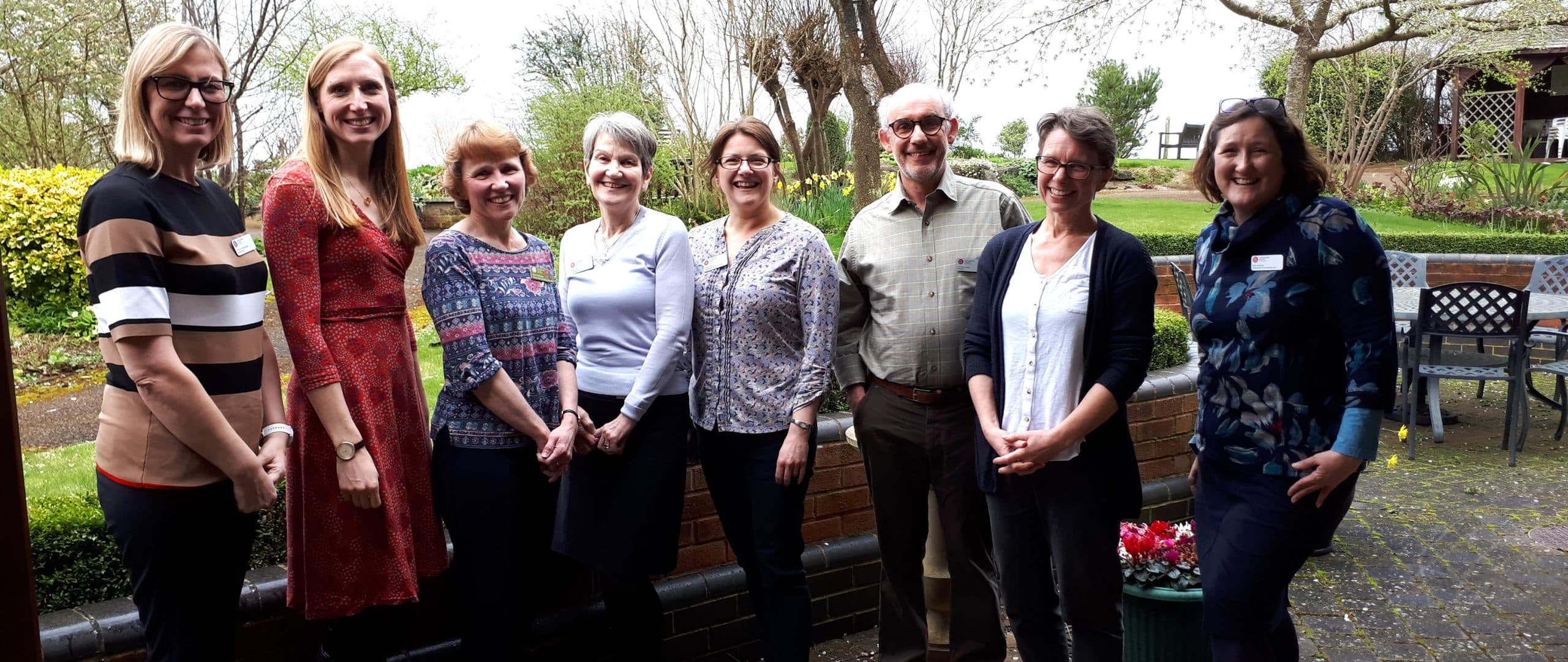 A group of eight people standing outdoors, smiling at the camera.