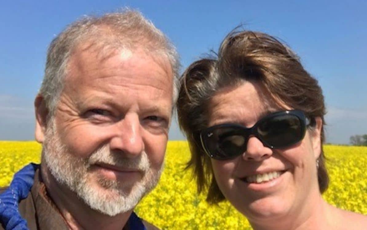 National legacy campaign A smiling couple in a field of yellow flowers under a clear blue sky.