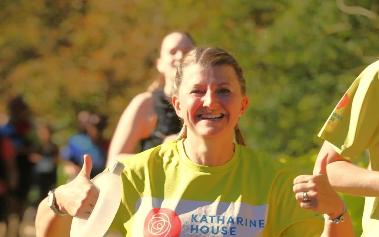 Smiling runner at the Oxford Half Marathon wearing a Katharine House Hospice T-shirt gives thumbs up.