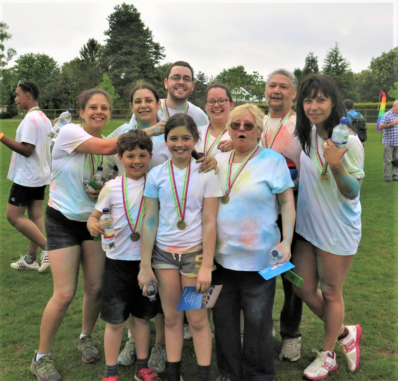 A group of people smiling outdoors, wearing medals and holding water bottles after completing the Katharine House Hospice moonlight walk.