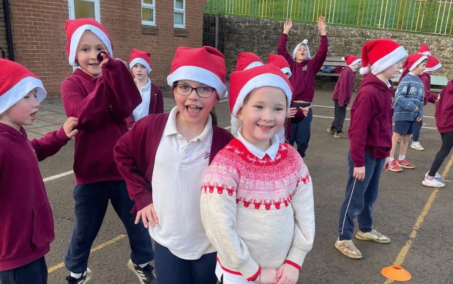 Schools Santa Run 2026 Group of smiling primary school children in the playground wearing Santa hats ready for the Katharine House Hospice Schools Santa Run.