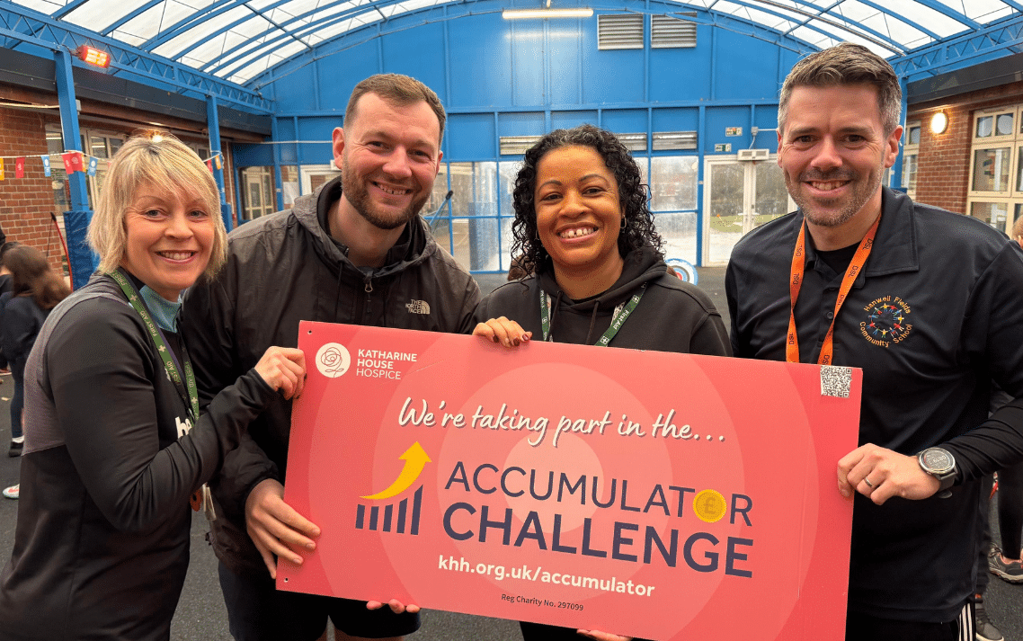 Hanwell Fields Community School Ac Four people wearing sports clothes holding a banner that says 'We're taking part in the Accumulator Challenge'.